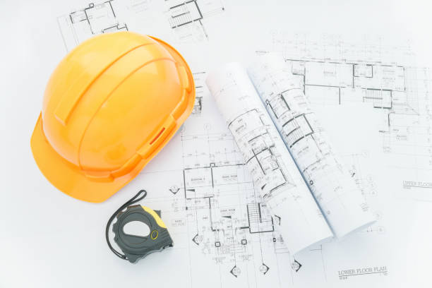 istock architects workplace - architectural blueprints with measuring tape, safety helmet and tools on table. top view 680188416