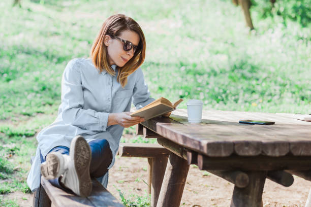 istock Woman reading a book in the park 680188756