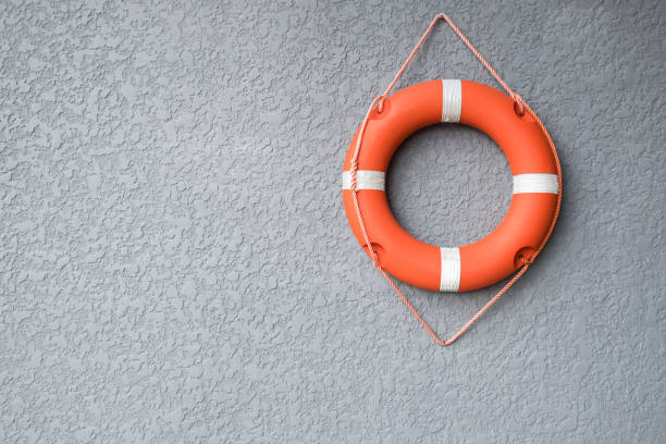 Orange life buoy hang on the grey wall Orange life buoy hang on the grey wall life jacket stock pictures, royalty-free photos & images