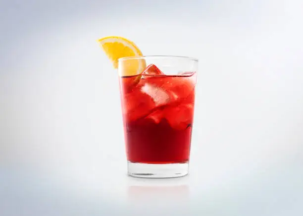 Photo of Negroni cocktail drink with ice cubes and orange. A glass with Campari (bitter).
