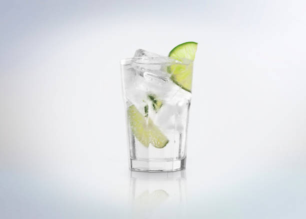 A glass of Gin Tonic cocktail  drink with ice cubes (on the rocks) and a slice of lime. Isolated on white background. gin tonic stock pictures, royalty-free photos & images