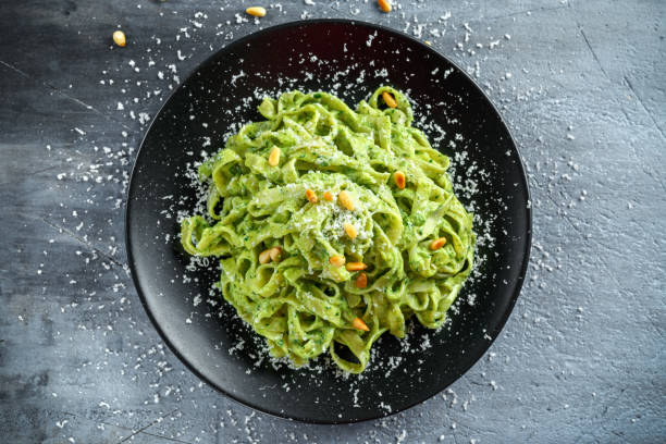 istock Tagliatelle pasta with pesto sauce, pine nuts and parmesan on black plate. 680220246