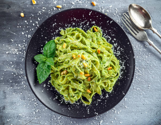 istock Tagliatelle pasta with pesto sauce, pine nuts and parmesan on black plate. 680220594