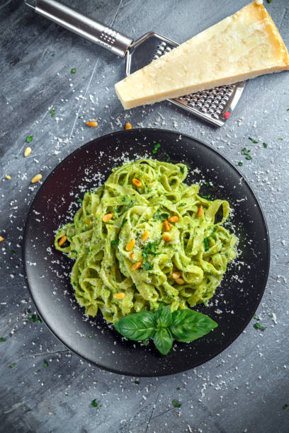 istock Tagliatelle pasta with pesto sauce, pine nuts and parmesan on black plate. 680221056