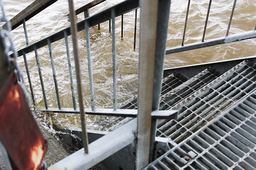 Water of a flooded area rising on the metal stairs