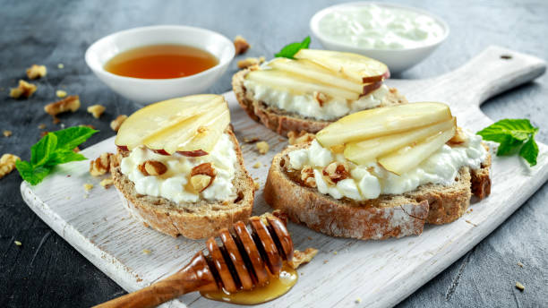 Appetizer bruschetta with pear, honey, walnut and cottage cheese on white board. Appetizer bruschetta with pear, honey, walnut and cottage cheese on white board crostini stock pictures, royalty-free photos & images