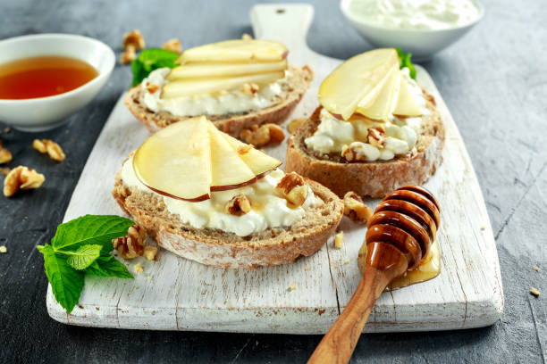 istock Appetizer bruschetta with pear, honey, walnut and cottage cheese on white board. 680225586