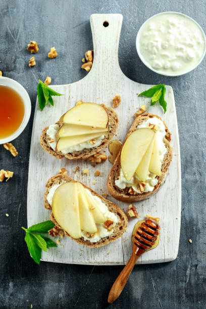 istock Appetizer bruschetta with pear, honey, walnut and cottage cheese on white board. 680226166