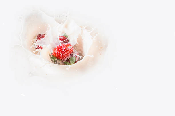 Splash from the falling strawberry in milk, lifting milk drops