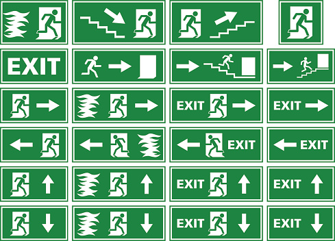 A collection of different variations of emergency exit signs / plates showing white silhouettes on green background. Various illustrations of a person or man running toward an exit door of a building to escape and find rescue, in some fleeing from a fire or flames. Some of the signs contain an arrow, stairs or the word 