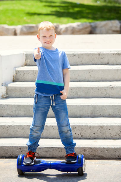 istock School Boy trying to balance on blue hoverboard 680248588