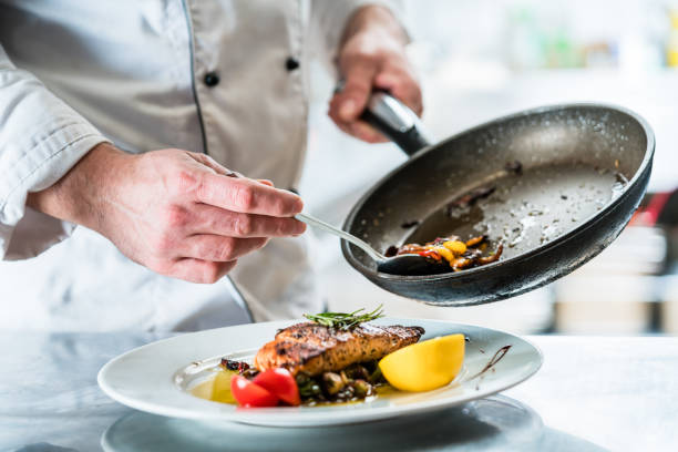 chef che termina il cibo nella cucina del suo ristorante - prepared fish foto e immagini stock