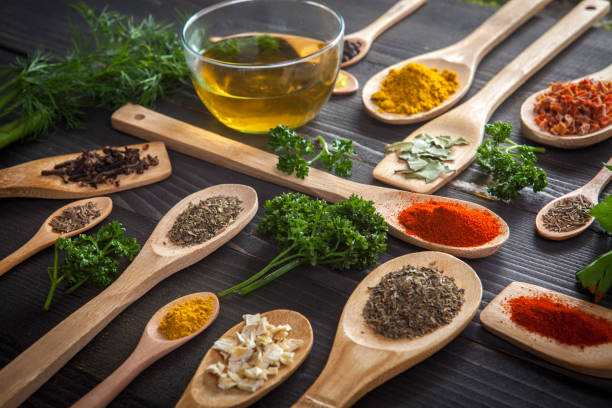 Various spice on wooden spoons with herbs stock photo