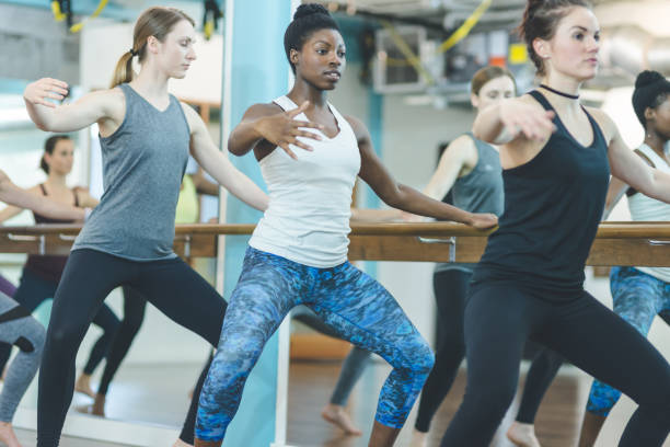 Multi-ethnic group of women doing barre workout Multiethnic group of young women do barre workout together at modern gym cropped pants photos stock pictures, royalty-free photos & images