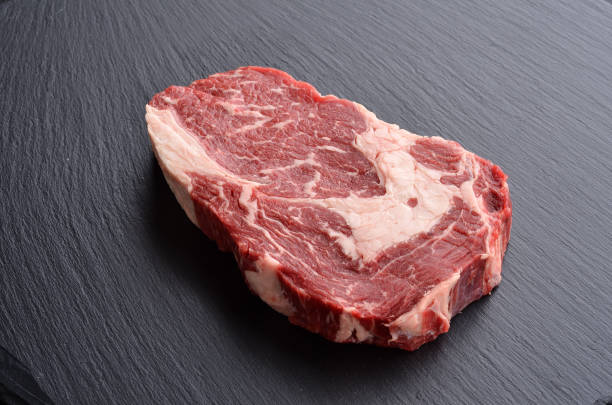 Fresh raw Prime Black Angus Rib Eye beef steak on stone background