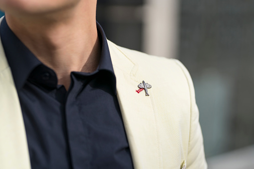 Close-up of an unrecognizable man in a shirt and tuxedo with an airplane brooch.