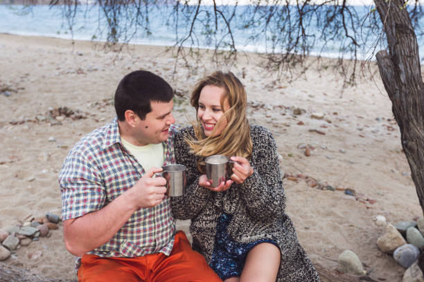 istock Happy couple drinking cocoa with marshmallows outdoors at the beach 680311898