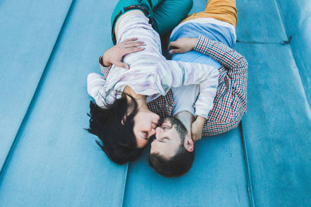 casal jovem hippie deitado no telhado e beijando. bela vista da cidade de cima. estilo casual - teenage girls ideas blue yellow - fotografias e filmes do acervo