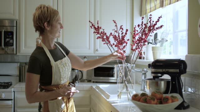Pretty Woman Arranging Flowers in the Kitchen