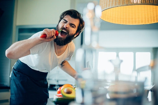 Handsome bearded man singing and having fun in the kitchen