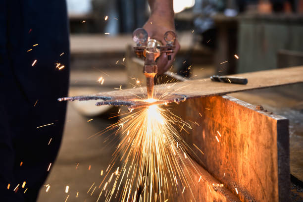 istock Worker cutting metalsheet by acetylene torch with bright sparks in fabication factory. 680334002
