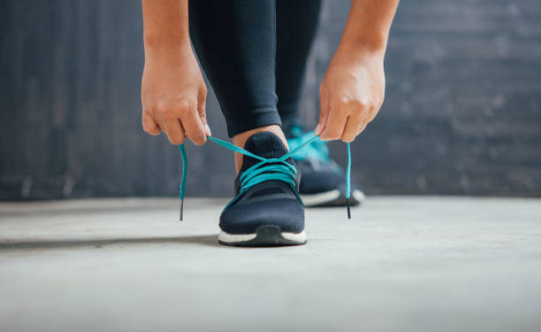 istock Female runner tying her shoes preparing for a run 680346404