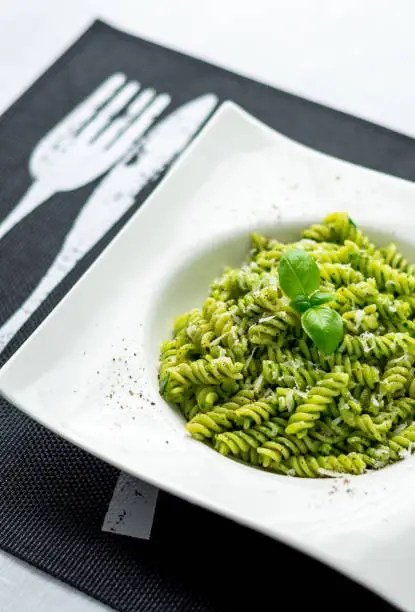 Basil pesto pasta vertical. Rotini pasta with basil pesto sauce, grated parmesan cheese and fresh pepper. This Italian dish makes a delicious meal by itself or can be used as a pasta salad side.