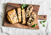 Mushroom and potato strudel on a rustic wooden cutting board, top view