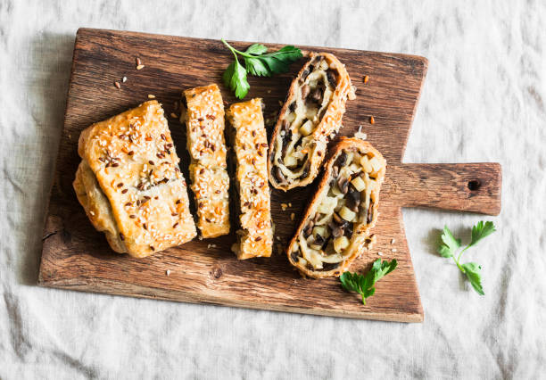 Mushroom and potato strudel on a rustic wooden cutting board, top view Mushroom and potato strudel on a rustic wooden cutting board, top view strudel stock pictures, royalty-free photos & images