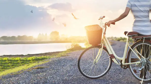 Photo of woman standing with vintage bicycle, relaxing in summer sunset nature rural with flying birds