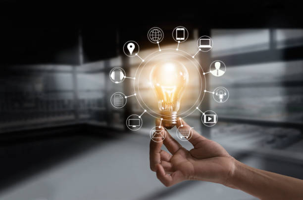 Hand holding light bulb with icons multimedia and customer network connection on dark room background
