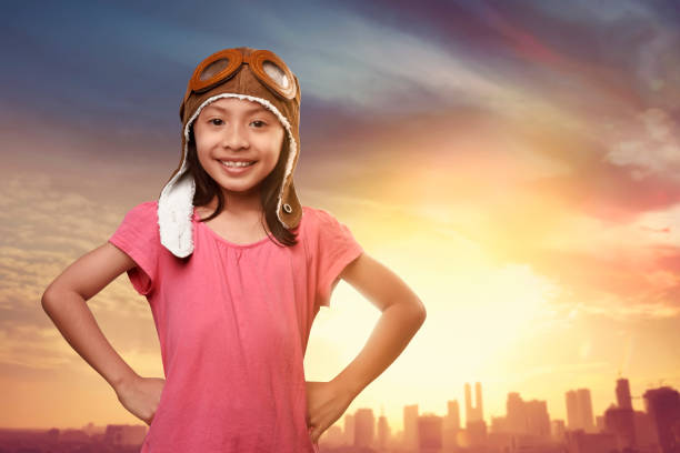 Little girl plays astronaut. Child on the background of sunset sky. Kid is looking at falling star and dreaming of becoming a spaceman.