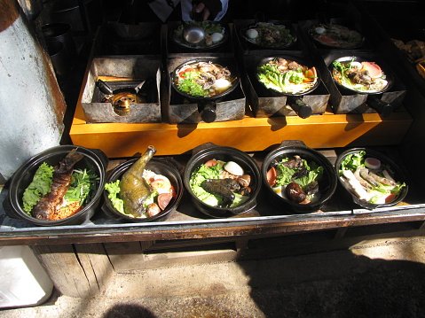 Variety of stewed dishes ready to be served on the streets of Lijiang