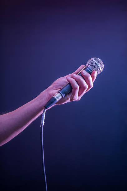 istock hand with microphone on a black background, the music concept, beautiful lighting on the stage 680368218