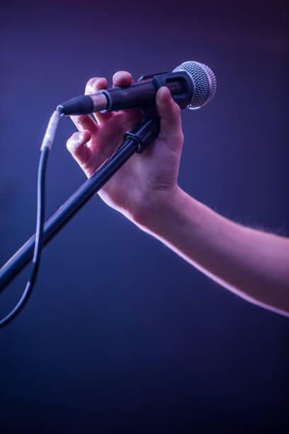 istock hand with microphone on a black background, the music concept, beautiful lighting on the stage 680368262