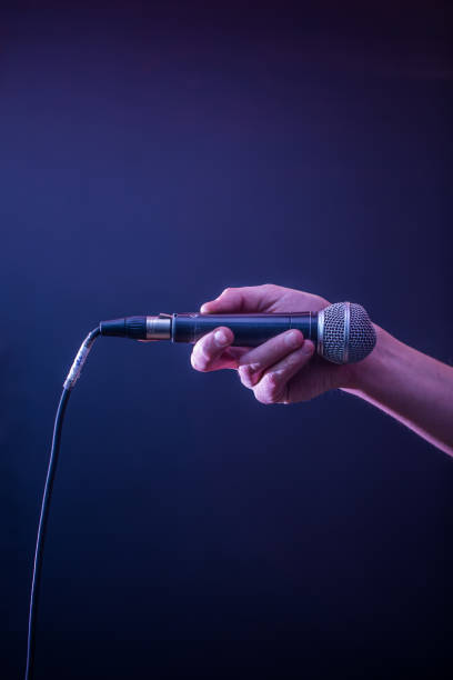 istock hand with microphone on a black background, the music concept, beautiful lighting on the stage 680368266