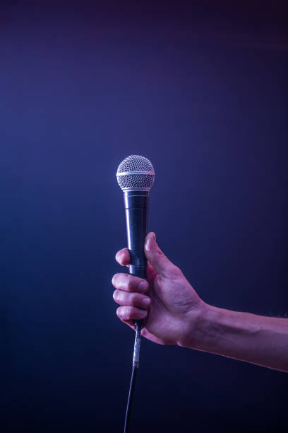istock hand with microphone on a black background, the music concept, beautiful lighting on the stage 680368272