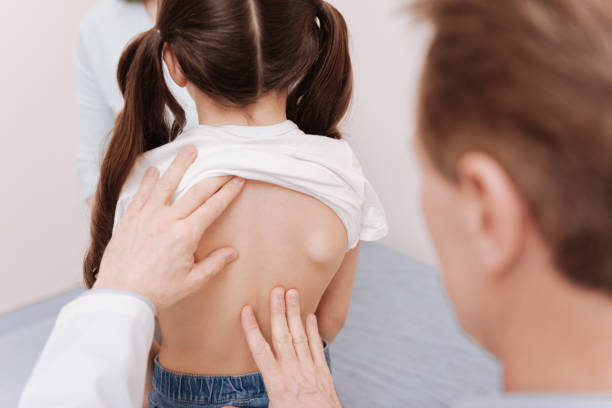 Gentle neat rheumatologist making sure girls spine being healthy Right posture development. Prominent polite local doctor running a checkup on little patients back and seeing no signs of problems anatomist photos stock pictures, royalty-free photos & images