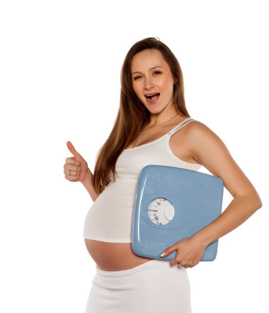 happy pregnant woman holding the scales on a white background - human hand hand sign measuring scale imagens e fotografias de stock