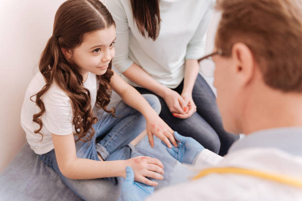 Pretty smart girl listening to experts instructions You should not scratch these. Charming sad lovely child sitting at doctors office for showing her hands hearing what the specialist prescribing her dermatology photos stock pictures, royalty-free photos & images