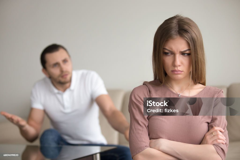 Angry husband mad at wife, unhappy woman frustrated, family conflict Unhappy family couple quarreling, angry husband complaining and blaming wife for problems, frustrated woman disagrees standing silent with arms crossed. Marital misunderstandings, lack of dialogue Disgust Stock Photo
