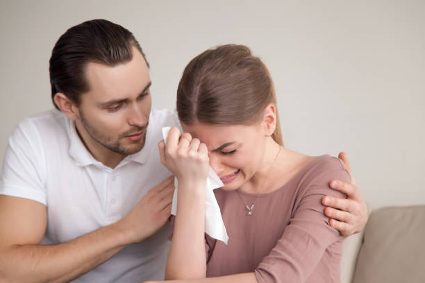 Husband comforting sad crying wife, man consoling sobbing young lady Upset crying woman wiping tears with handkerchief, loving boyfriend trying to comfort girlfriend embracing her, husband consoling depressed wife, support in difficult situation, compassion wiping tears stock pictures, royalty-free photos & images