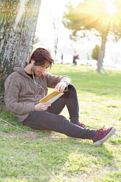 istock Young man reading book in the park 680413224