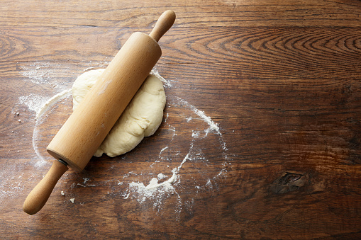 Rolling out a piece of dough to make dumplings on a wooden board with flour photo