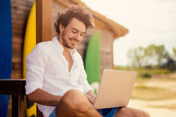 istock Attractive man using a laptop at a beach bar 680427494