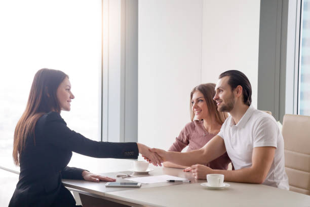 不動産取引、エージェントとのハンドシェイクを作る幸せな若いカップル - business relationship handshake business meeting ストックフォトと画像