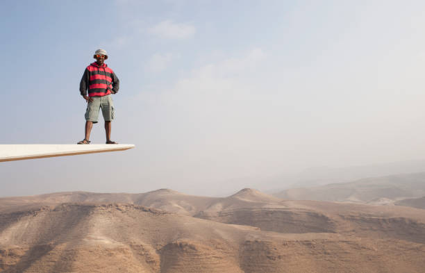 Traveller man with hands on waist standing on platform with scenic view of desert hills.