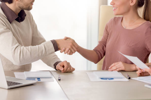 istock Young smiling business partners shaking hands, group meeting in office 680437332