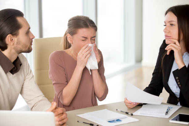 young businesswoman holding handkerchief sneezing during meeting with colleagues - russian influenza epidemic virus flu virus imagens e fotografias de stock