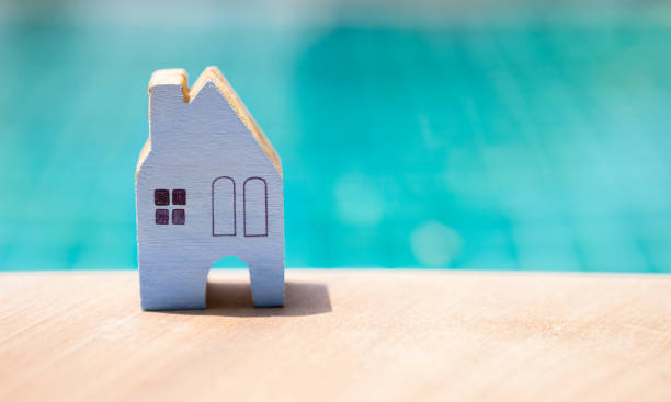 istock Miniature blue wooden house over blurred blue swimming pool 680437526